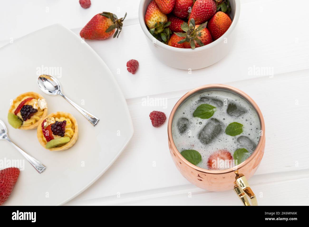 cibo delizioso, tavolo servito con tè freddo, piatto con torta decorata con frutta fresca e fragole, cibo e bevande gourmet, sfondo Foto Stock