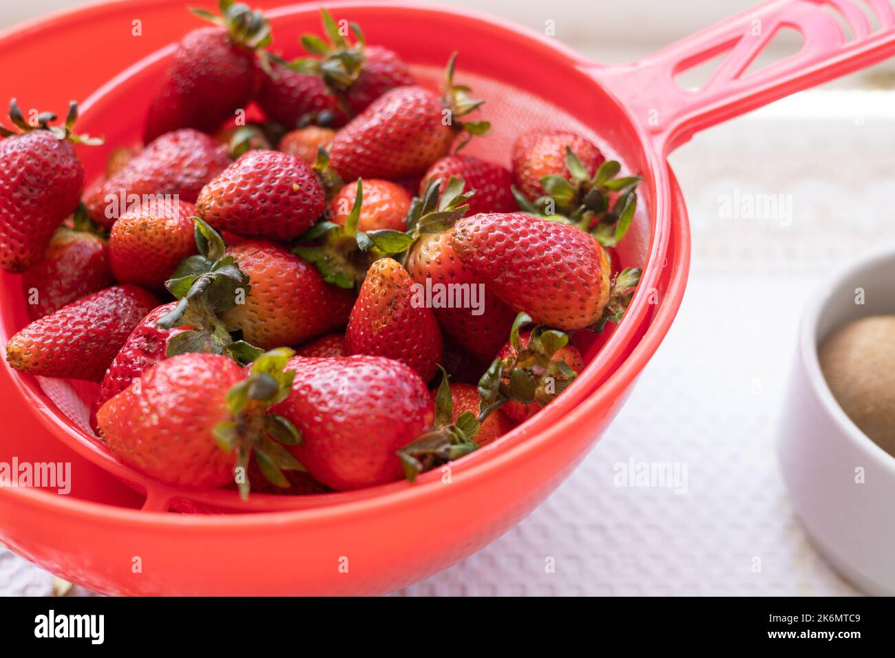 dettagli della consistenza della fragola, frutta tropicale lavata per preparare il cibo in un colander, cibo sano e biologico Foto Stock