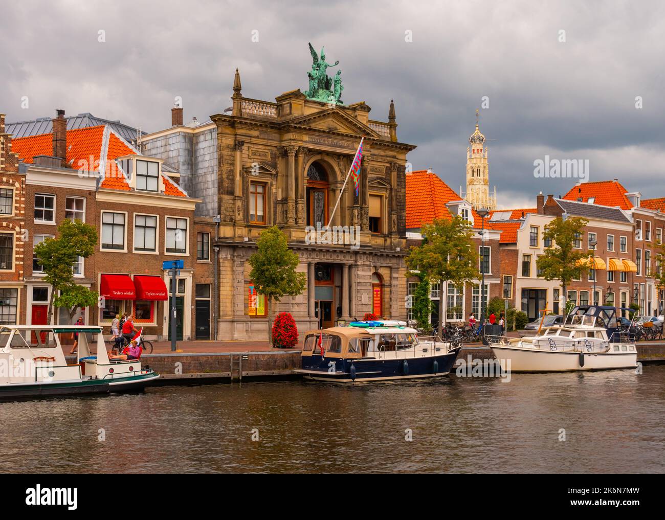 Il lungomare di Haarlem lungo il fiume Spaarne con il Museo Teylers e la torre Bakenesserkerk sullo sfondo Foto Stock