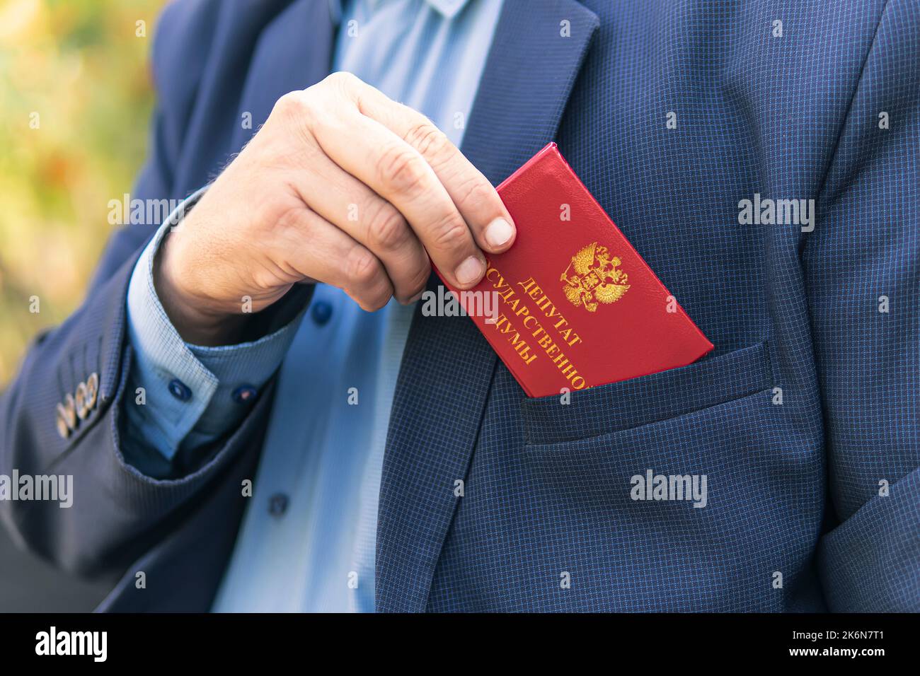 Concetto di immunità parlamentare. L'uomo in abito blu mostra una carta d'identità rossa o un pass. Un importante dipendente intoccabile del ministero sta guidando un'automobile. duma di stato Foto Stock