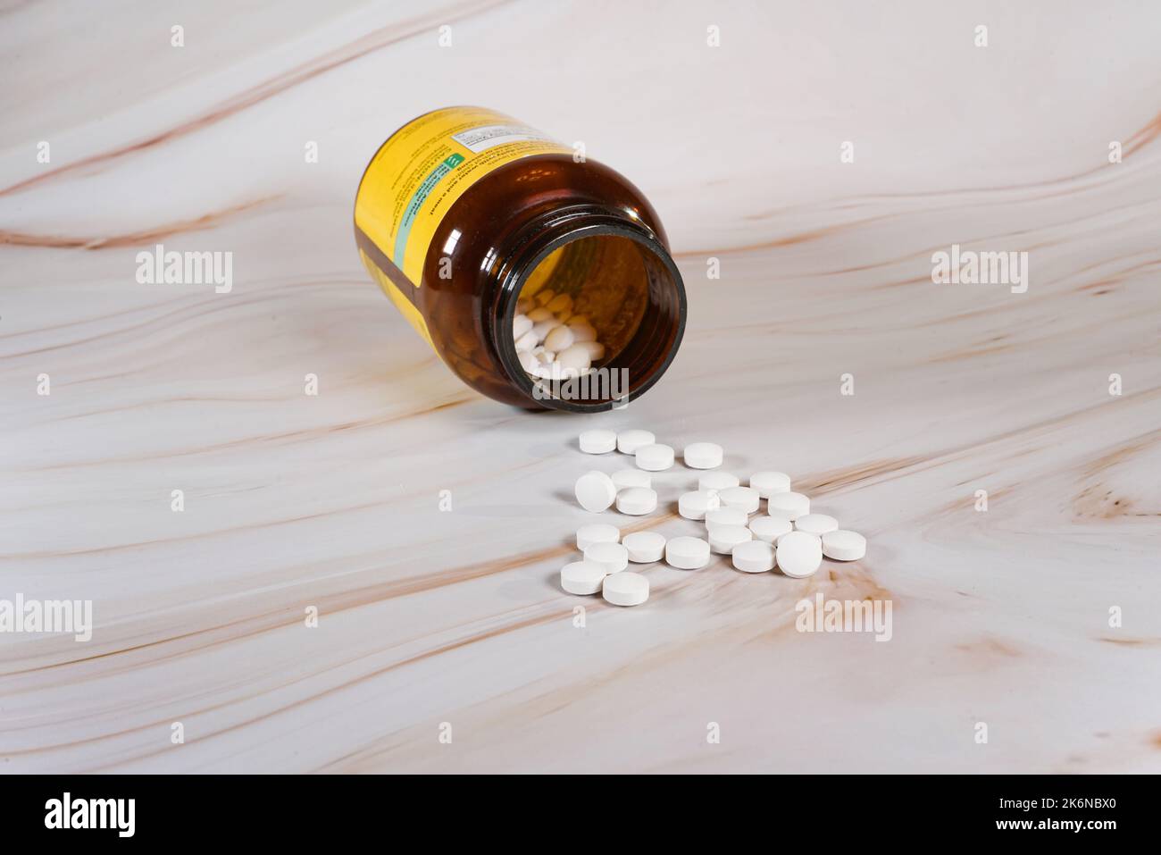 Compresse di vitamina D rovesciato contenitore aperto sul banco di marmo. Foto Stock