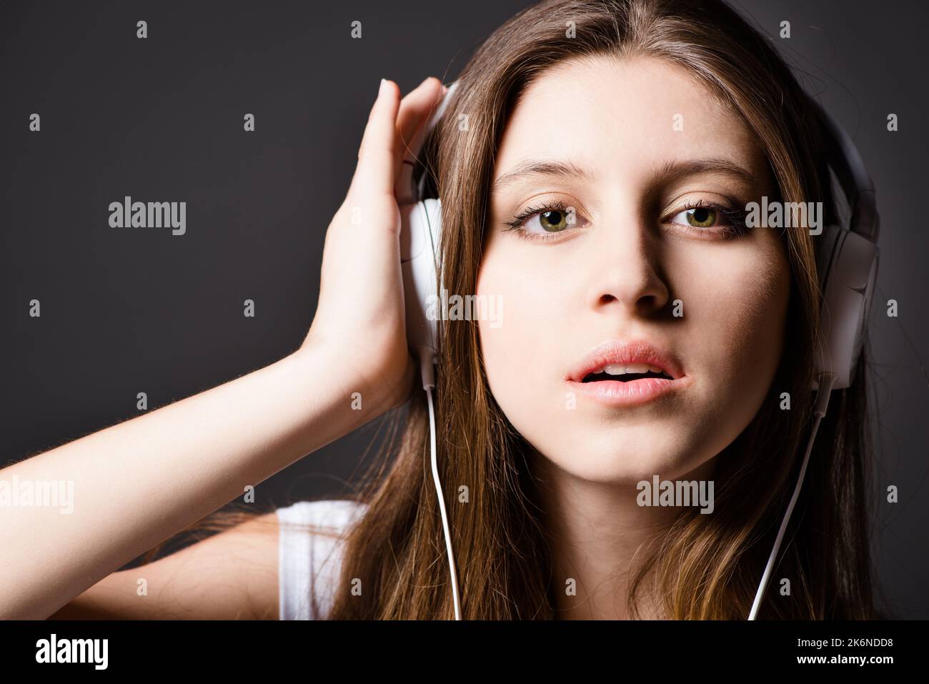 Facile da indossare, facile da sentire. una giovane donna che ascolta musica sullo sfondo di uno studio. Foto Stock