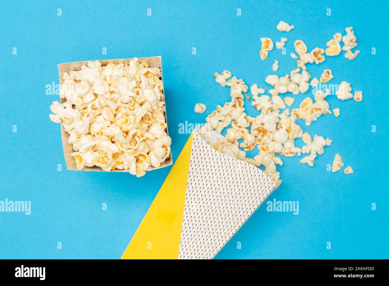 Concetto snack, popcorn dolce in tazza di carta e fuoriuscita dalla tazza di carta su sfondo azzurro. Foto Stock