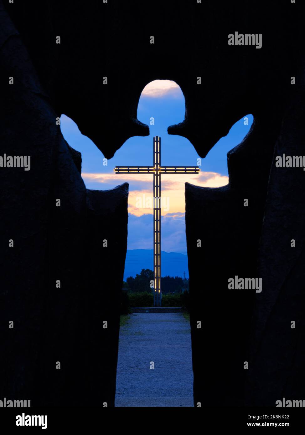 Brezje, Slovenia - 28 luglio 2022: Un'ora blu attraverso la silhouette del bambino Gesù su una grande croce illuminata Foto Stock
