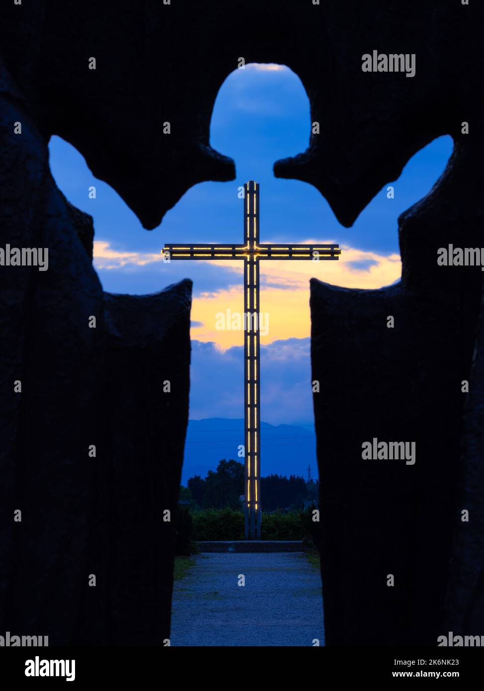 Brezje, Slovenia - 28 luglio 2022: Un'ora blu attraverso la silhouette del bambino Gesù su una grande croce illuminata Foto Stock