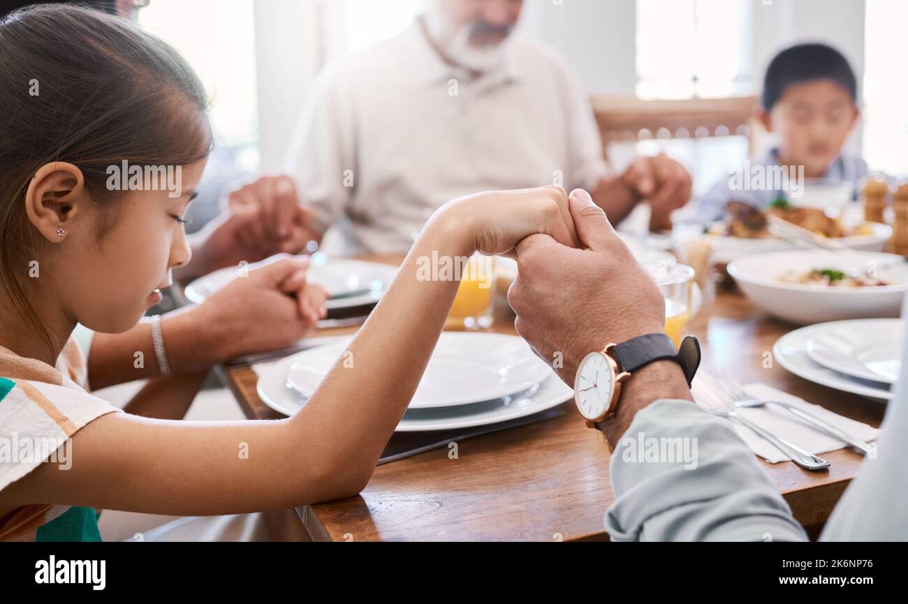 Trasmettete ai nostri figli il valore dell'empatia. una bella famiglia benedice il cibo con una preghiera al tavolo insieme a casa. Foto Stock