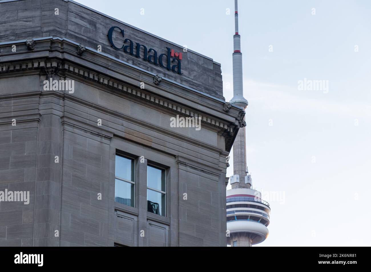 Il logo del Governo del Canada è visto in cima ad un edificio, il Dominion Public Building, nel centro di Toronto con la CN Tower sullo sfondo. Foto Stock
