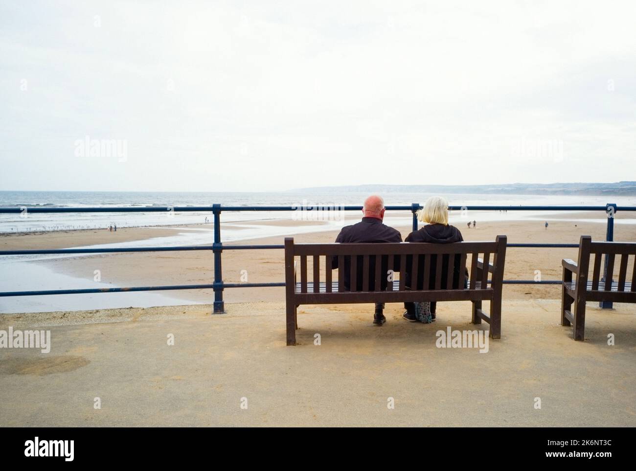 Una coppia più anziana seduta su una panchina che si affaccia sulla baia di Filey nel North Yorkshire Foto Stock