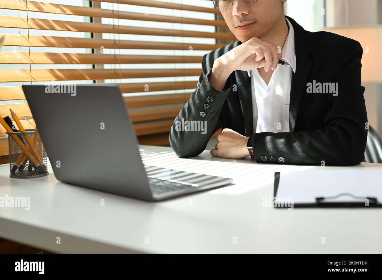 Uomo d'affari concentrato che analizza i dati finanziari on-line sullo schermo del computer portatile Foto Stock