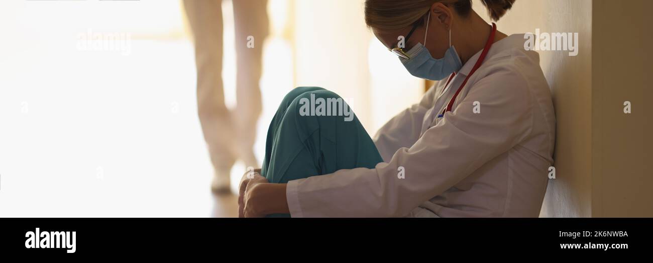 Una dottoressa è seduta sul pavimento nel corridoio, primo piano Foto Stock