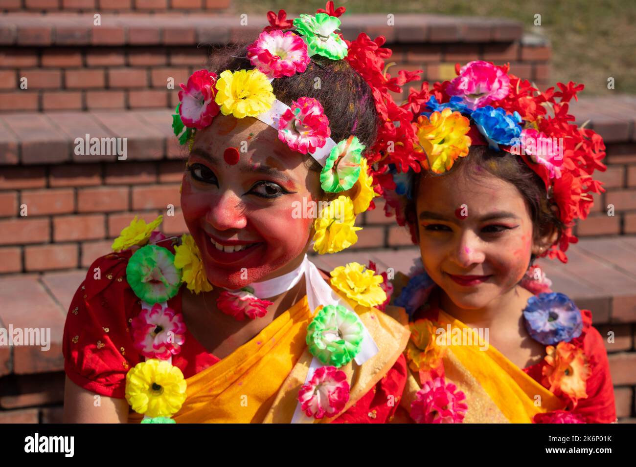 Le donne indossano abiti tradizionali con ornamenti floreali e si esibiscono durante il Festival di Primavera, il primo giorno del mese di Primavera del Bengalese ''Falgun'''. Foto Stock