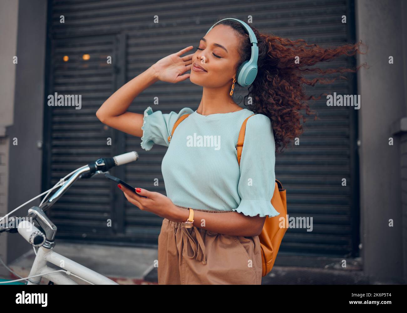 Bicicletta, telefono e donna nera con cuffie in città streaming audio, musica o podcast. Felice, viaggio e femmina dal Sudafrica con moto, 5g Foto Stock