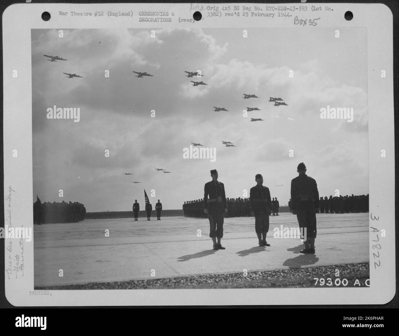 Uomini del 830th distaccamento ingegneri Stand at Attention come Boeing B-17S Fly overhead durante le cerimonie dedicate Un nuovo aeroporto a Nuthampstead, Inghilterra il 17 giugno 1943. Foto Stock