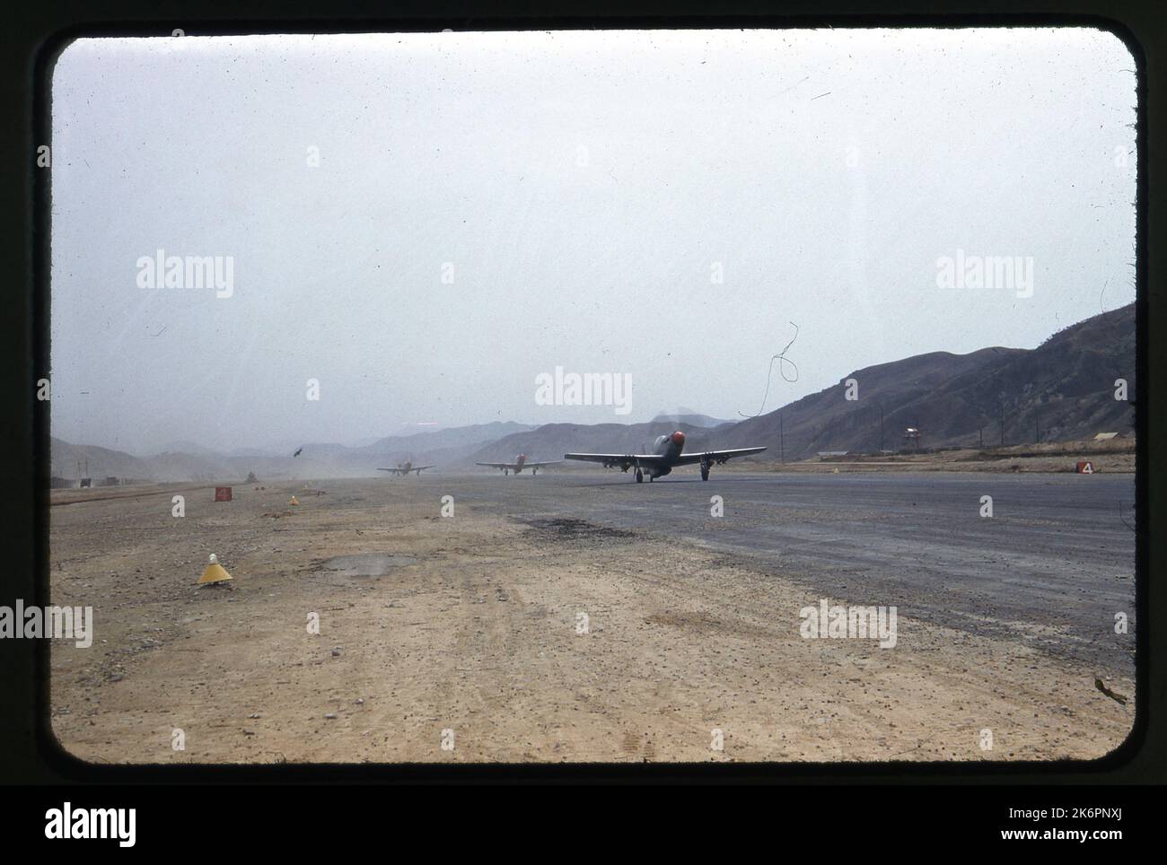Vista anteriore destra di tre quarti di un Mustang MK nordamericano. IV tassazioni, da qualche parte in Corea. Altri due Mustang Mk. IVS seguitelo lungo la pista. Gli aerei recano le marcature dell'aeronautica sudafricana e sono tutti armati di due bombe e quattro razzi. Foto Stock
