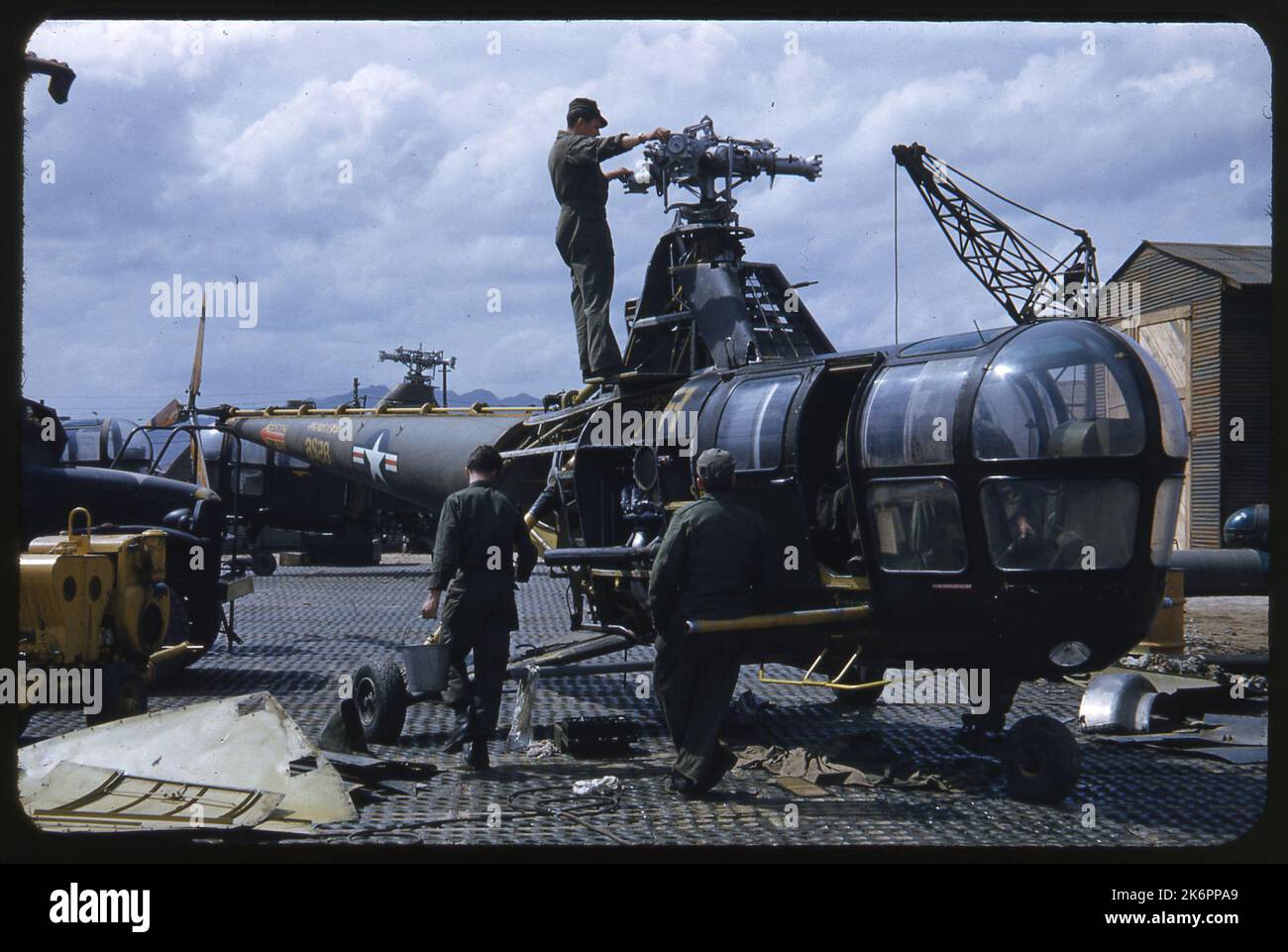 Un tecnico si trova in cima al Sikorsky H-5G Dragonfly (s/n 48-526), esaminando il motore, un altro si appoggia contro di esso, guardando l'altro lavoro, mentre un terzo cammina trasportando un secchio. Un tecnico si trova in cima al Sikorsky H-5G Dragonfly (s/n 48-526), esaminando il motore, un altro si appoggia contro di esso, guardando l'altro lavoro, mentre un terzo cammina trasportando un secchio. Foto Stock