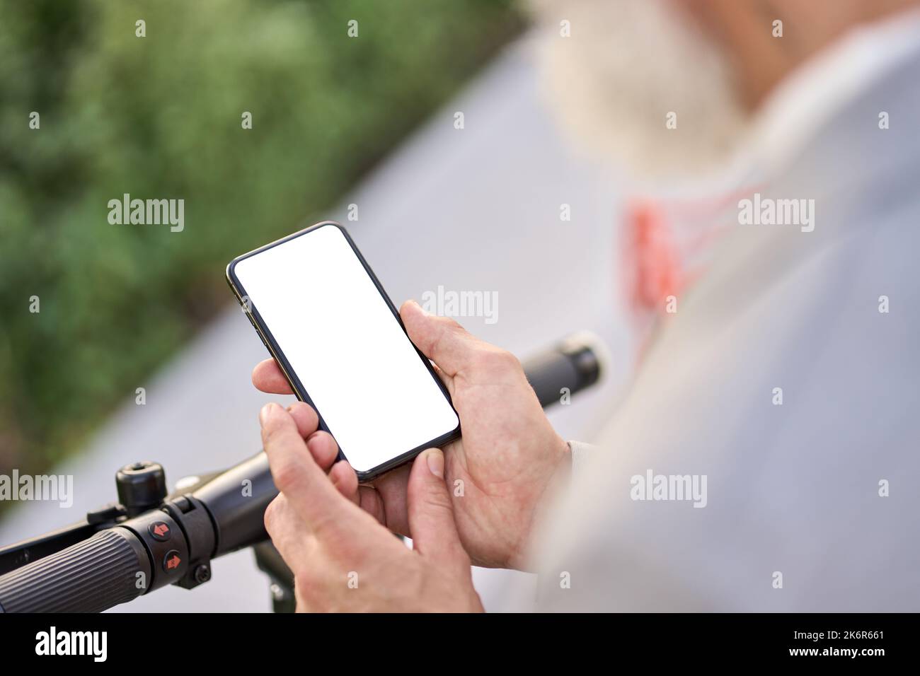 Uomo che tiene lo schermo mockup smartphone utilizzando l'app mobile per il noleggio di biciclette elettriche. Foto Stock