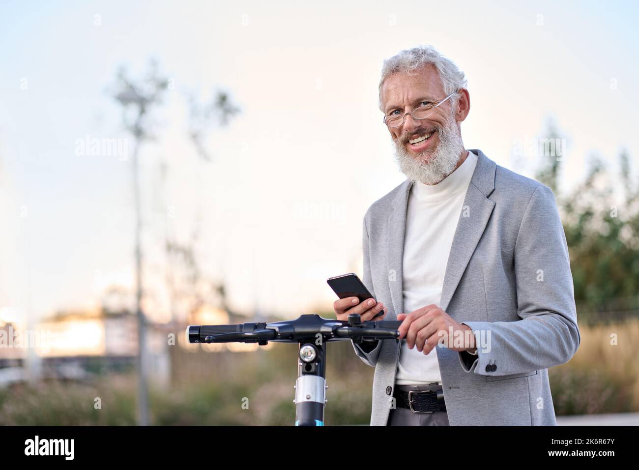 Buon vecchio utilizzando l'app mobile per il noleggio di biciclette nel parco cittadino. Foto Stock