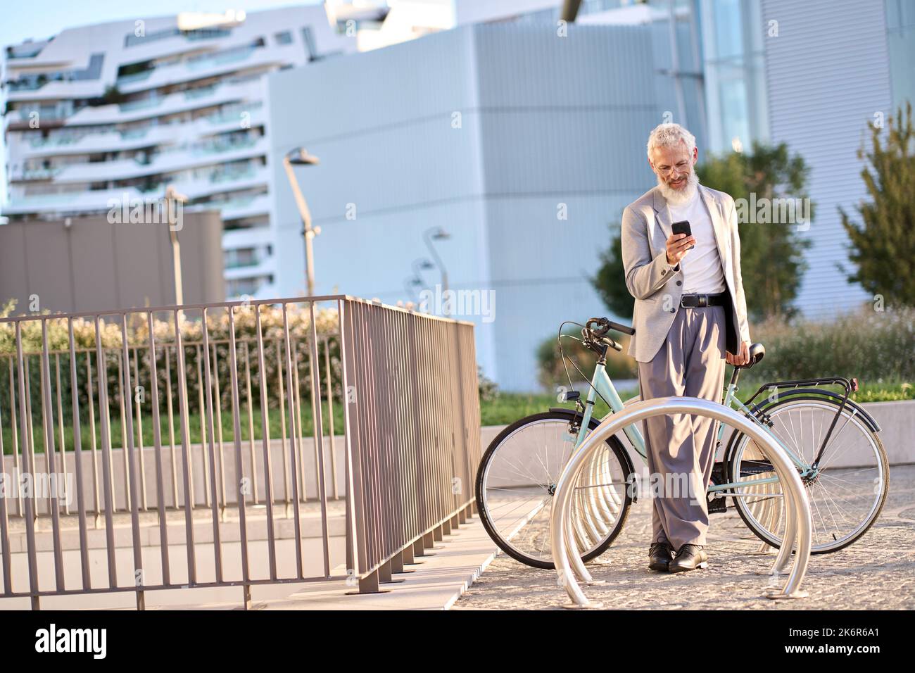 Vecchio uomo anziano che utilizza il telefono utilizzando l'app di noleggio biciclette noleggio biciclette nel parco cittadino. Foto Stock