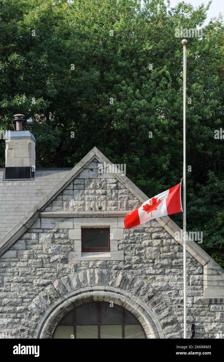 Un edificio accanto alle chiuse del canale Rideau nel centro di Ottawa, con la bandiera canadese che batte mezzo albero. Foto Stock