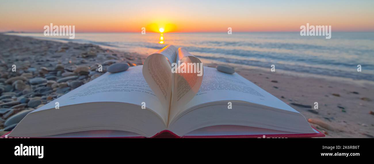 Zenith sulla spiaggia. Libro ripiegato a forma di cuore con alba. Foto Stock