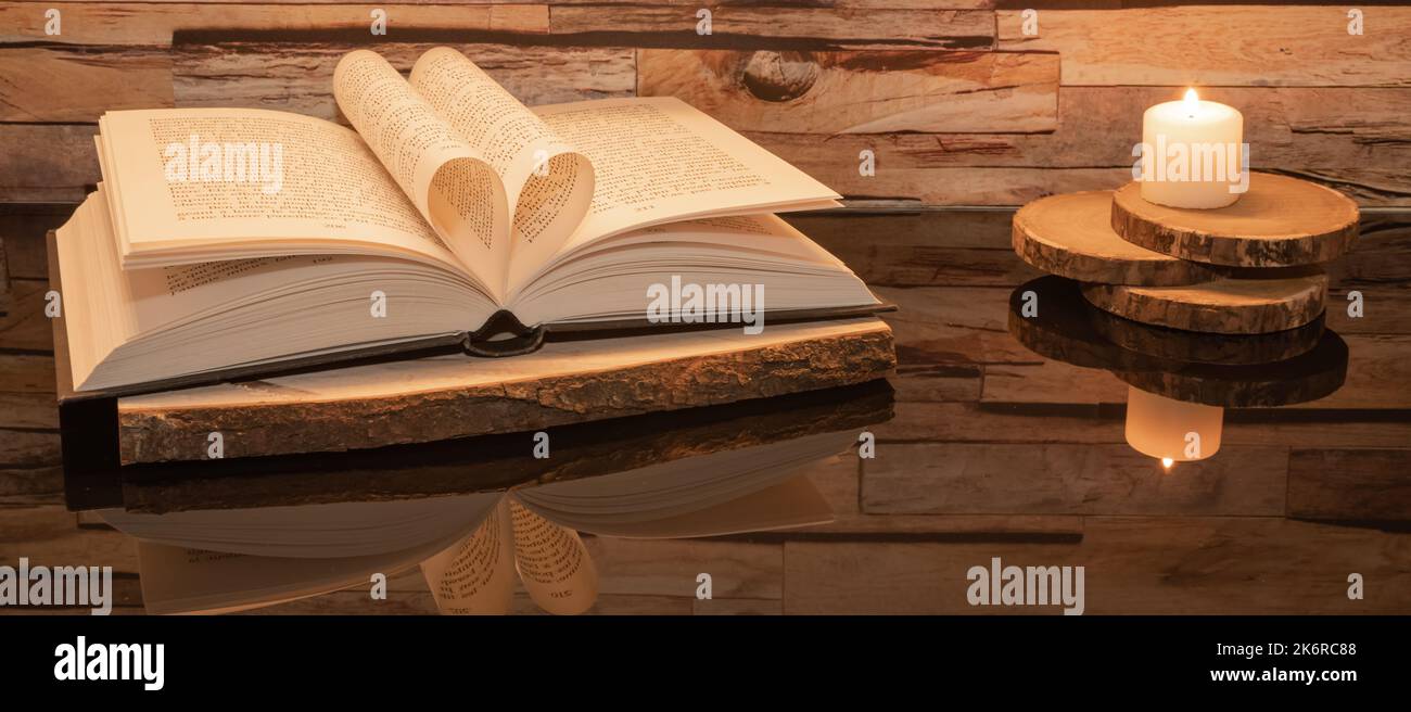 Libro ripiegato a forma di cuore su sfondo ligneo con riflessi. Foto Stock