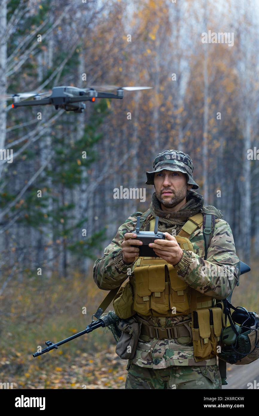 Il mercenario lancia un drone di ricognizione in una foresta. Moderni metodi tecnologici di ricognizione e di guerra. Foto verticale. Foto Stock