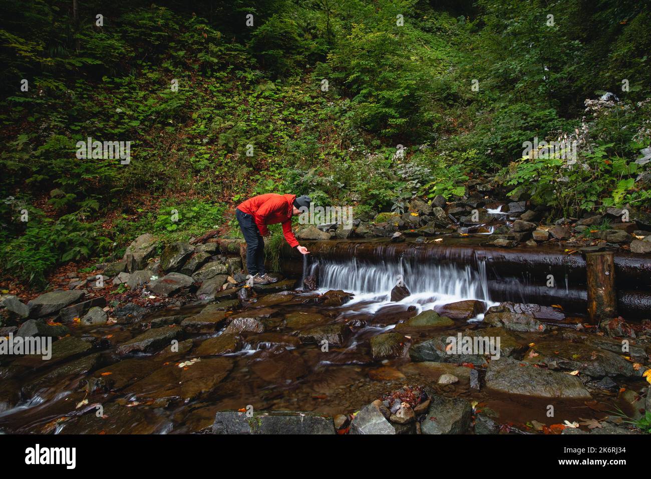 L'escursionista su un lungo sentiero ricarica l'acqua potabile da una sorgente di montagna in un contenitore di vetro. Rifornire di acqua pulita per cucinare e bere mentre ciao Foto Stock