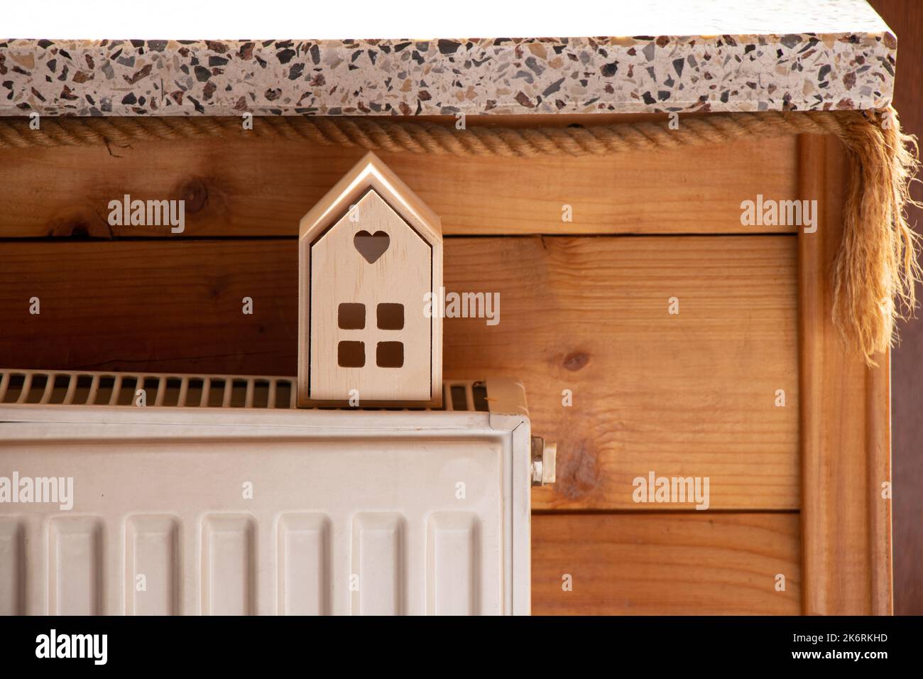Una piccola casa in legno si trova su batterie in un appartamento vicino alla finestra, una casa calda, riscaldamento centralizzato Foto Stock