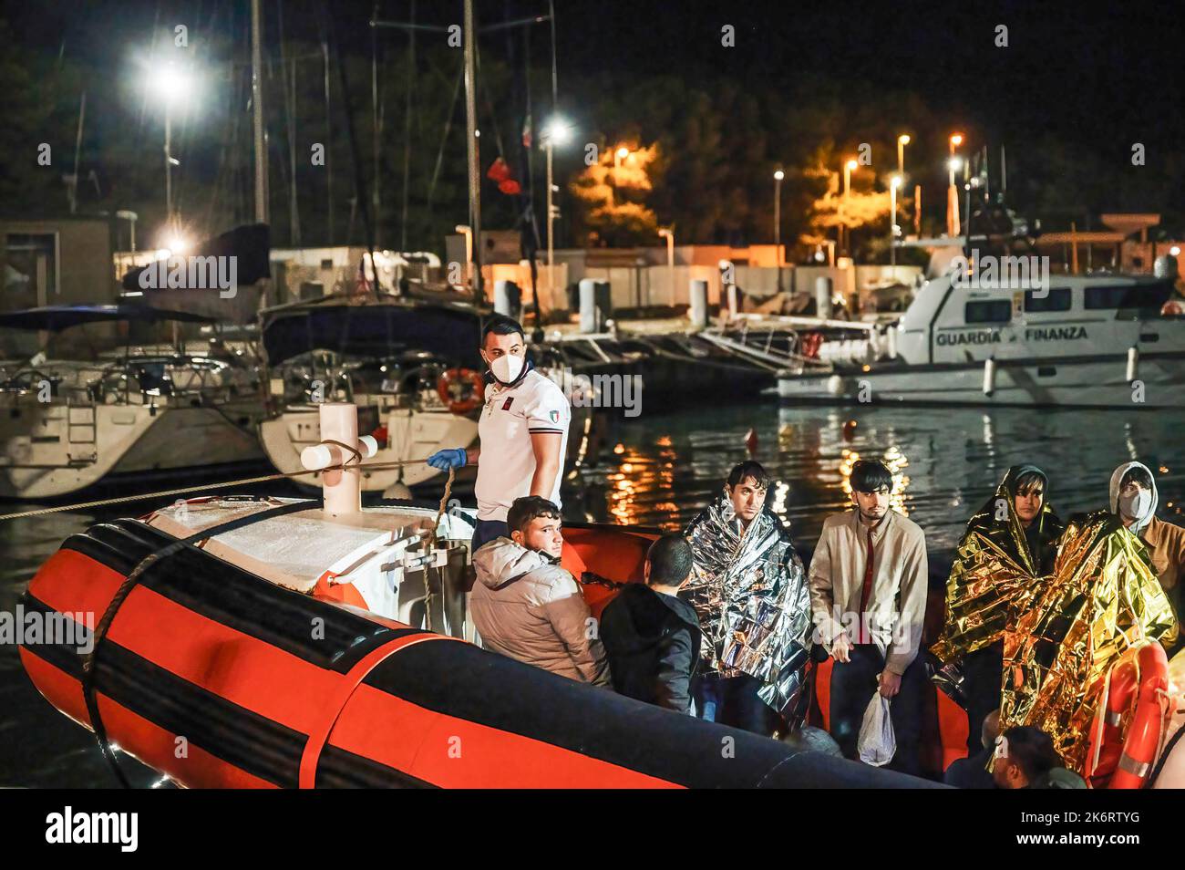 Roccella Jonica, Italia. 14th Ott 2022. Migranti visti con coperte termali su una barca di pattuglia. 64 migranti irregolari, provenienti principalmente da Afghanistan, Iran, Siria e Iraq, sono stati aiutati dalla Guardia Costiera Italiana e sbarcati a “Porto delle grazie”, il porto di Roccella Ionica, arrivando dalla Turchia. Le persone sono state assistite da Medici senza frontiere e dal comitato locale della Croce Rossa Credit: SOPA Images Limited/Alamy Live News Foto Stock