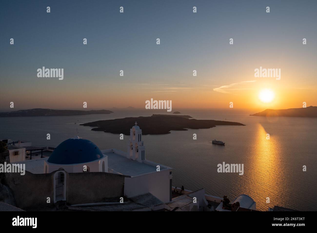 Vista del tramonto con le tre campane di Fira, ufficialmente conosciuta come la chiesa cattolica della Dormizione, con la sua tradizionale cupola blu sopra il cl Foto Stock