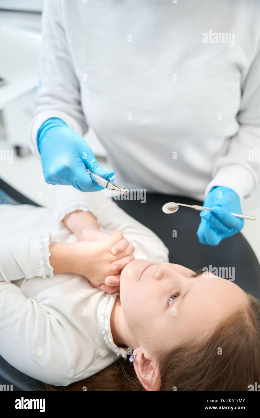 Piccolo paziente che chiede al chirurgo dentale la misericordia prima dell'estrazione del dente Foto Stock