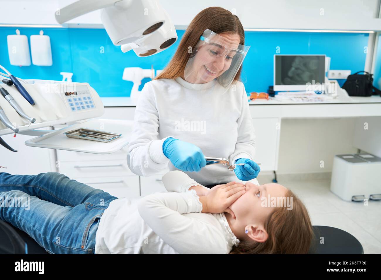 Chirurgo dentale ridendo di capriccioso piccolo paziente Foto Stock