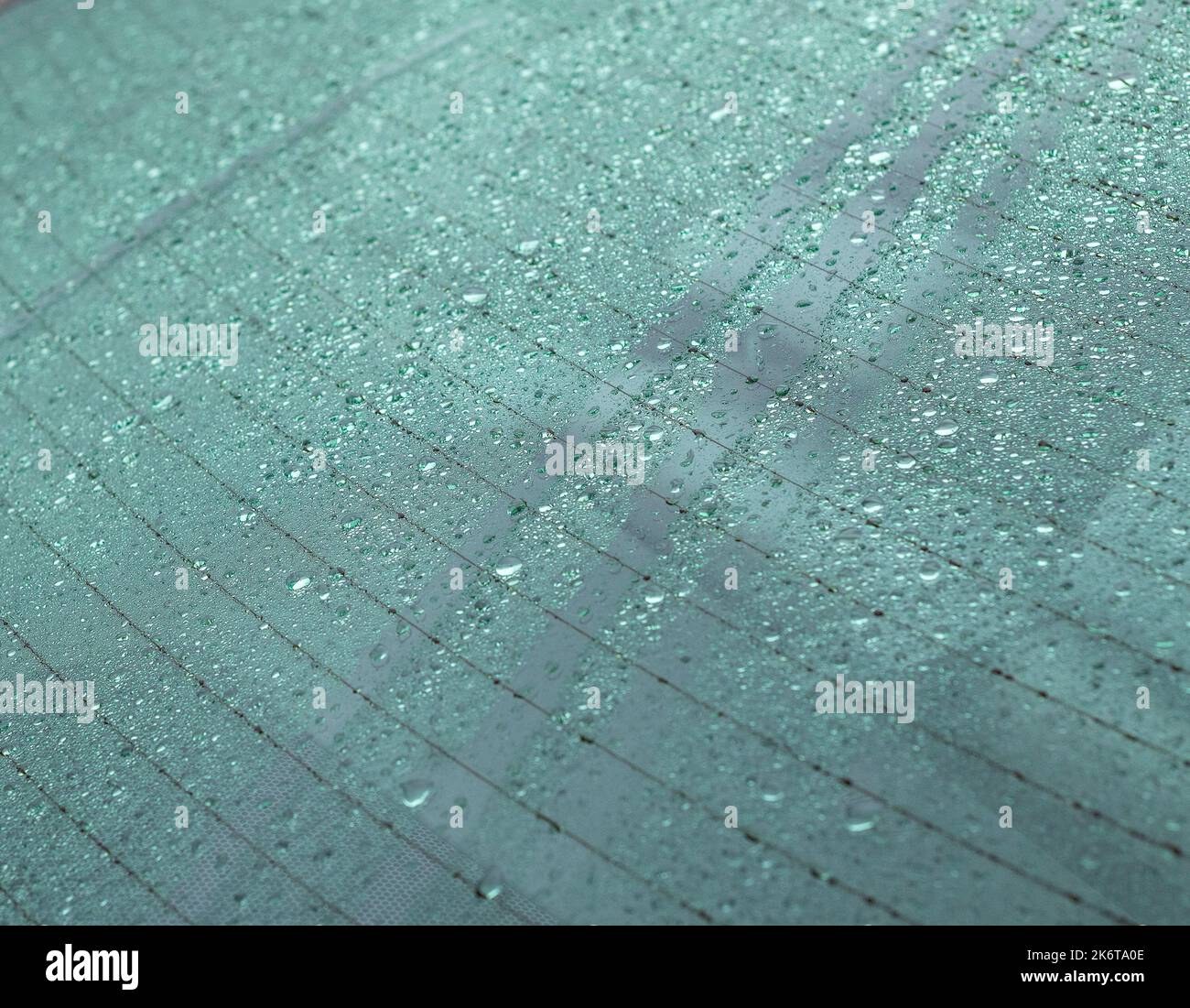 Primo piano delle gocce di pioggia sul parabrezza posteriore di un'auto. Foto Stock