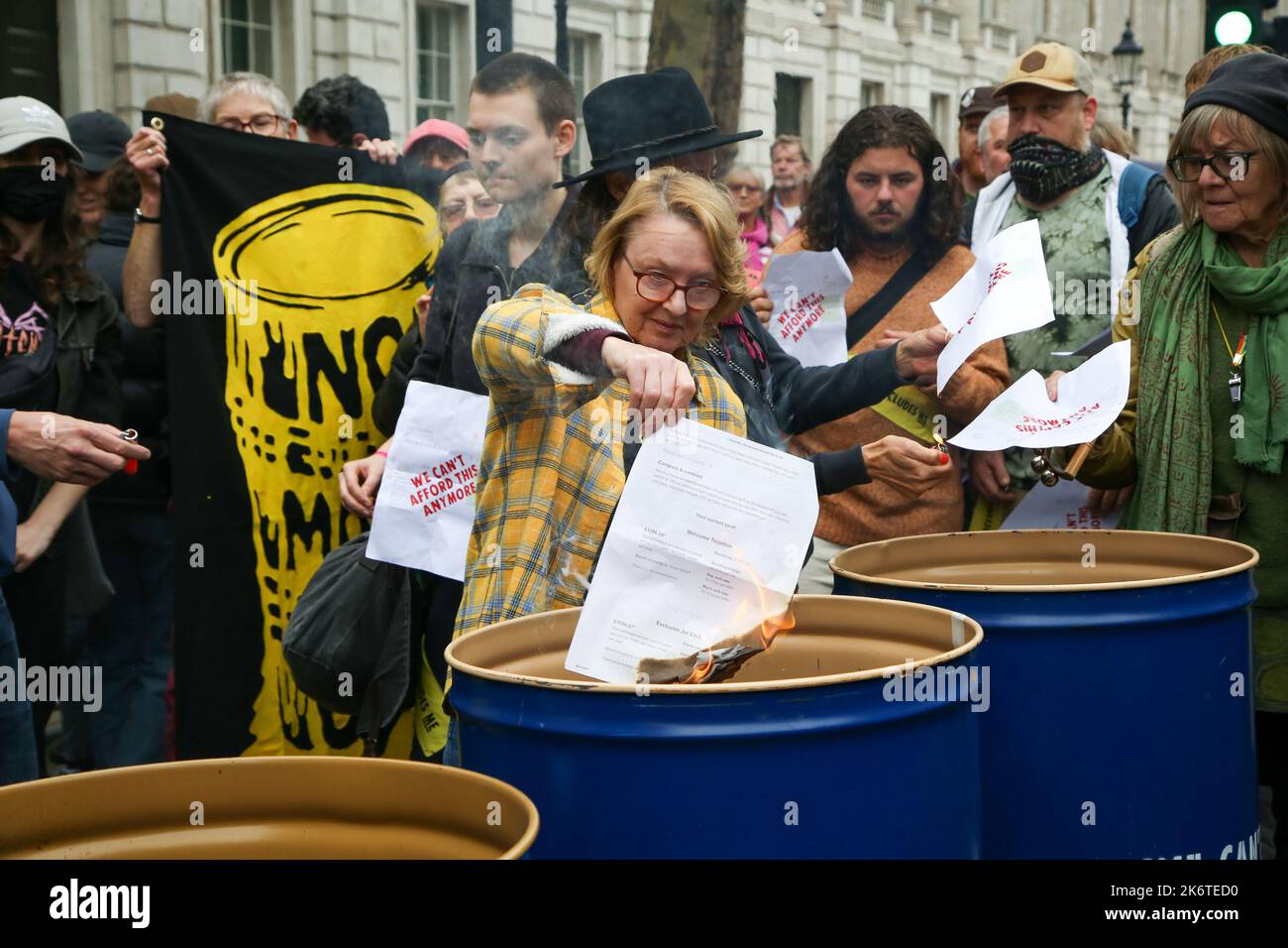 Londra, Regno Unito. 14th Ott 2022. Un protester della ribellione di estinzione brucia una bolletta energetica come i sostenitori dimostrano fuori Downing Street contro la crisi del cambiamento climatico e l'aumento delle bollette energetiche. Credit: SOPA Images Limited/Alamy Live News Foto Stock