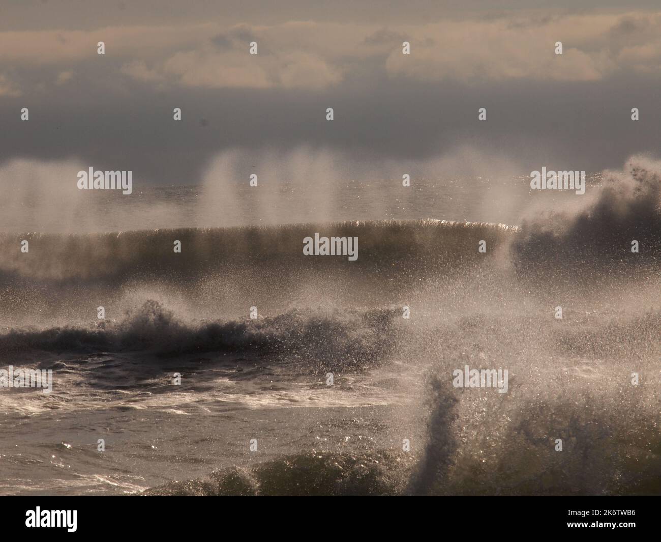 La tempesta ha gettato le onde che si schiantano contro la costa del New Jersey con il vento che soffia le loro cime fuori. Con la retroilluminazione, le forme d'onda appaiono trasparenti. Foto Stock