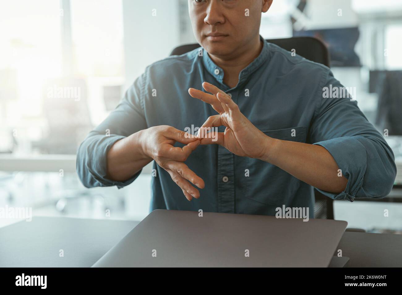 Primo piano dell'uomo d'affari che usa il linguaggio dei segni mentre parla con il cliente seduto in ufficio Foto Stock