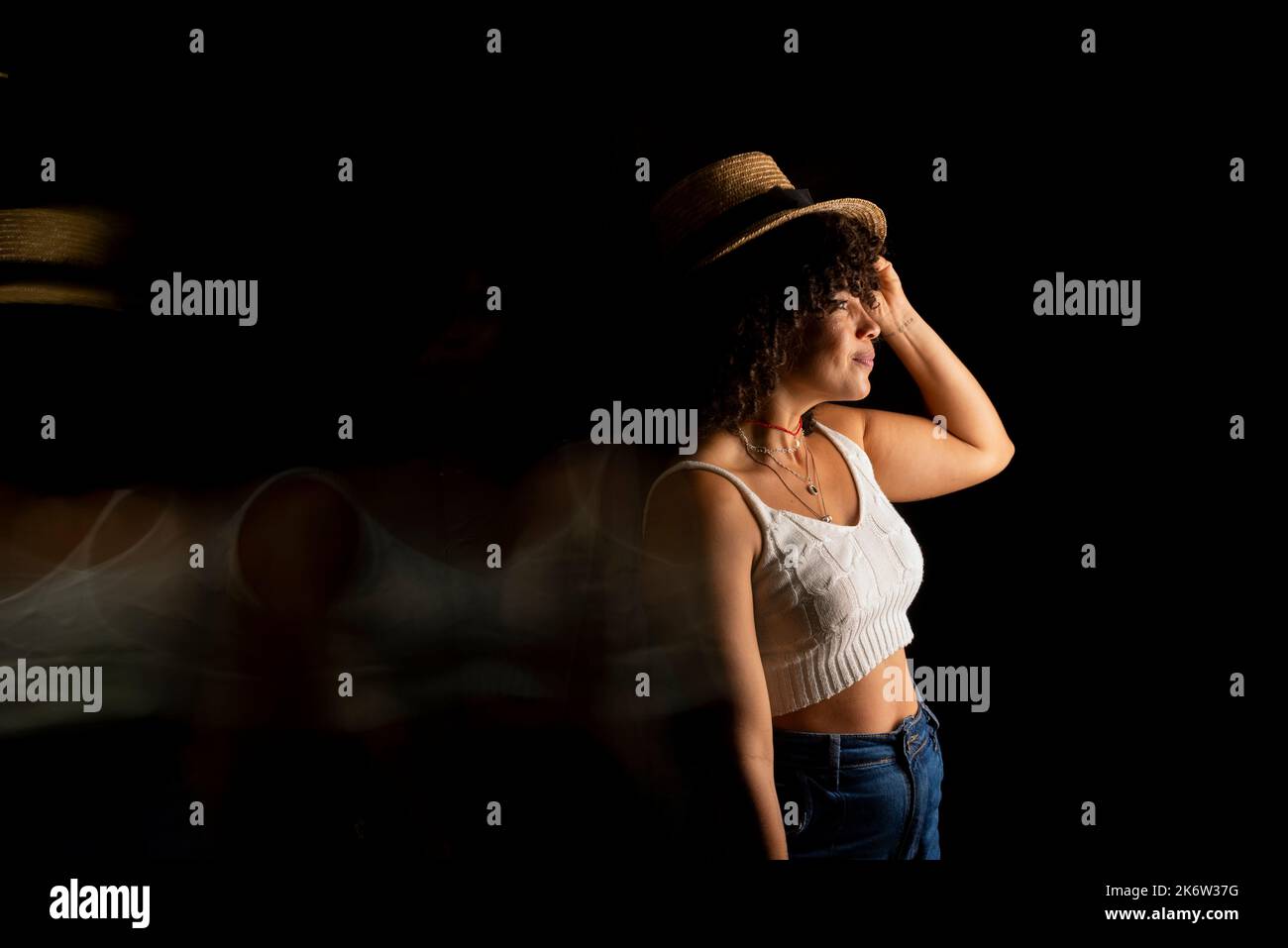 Vista temporizzata della donna che muove un cappello. Esposizione lunga, sfocatura del movimento. Donna felice. Salvador, Brasile. Foto Stock