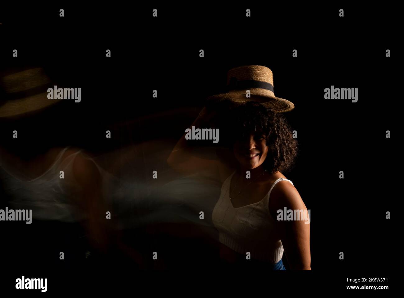 Vista temporizzata della donna che muove un cappello. Esposizione lunga, sfocatura del movimento. Donna felice. Salvador, Brasile. Foto Stock