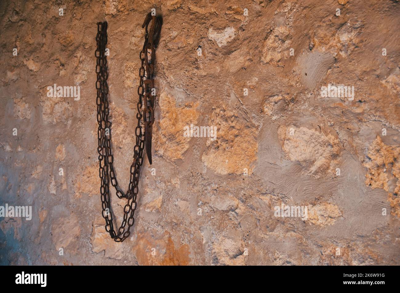 Vecchia catena di ferro arrugginita appesa al muro di pietra Foto Stock