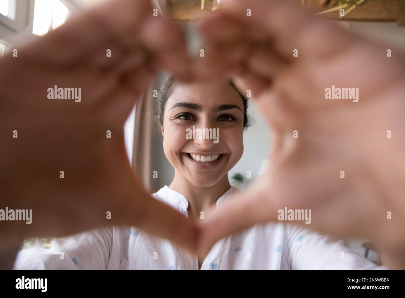 Ritratto di felice donna indiana si unisce dita mostrando simbolo di amore Foto Stock