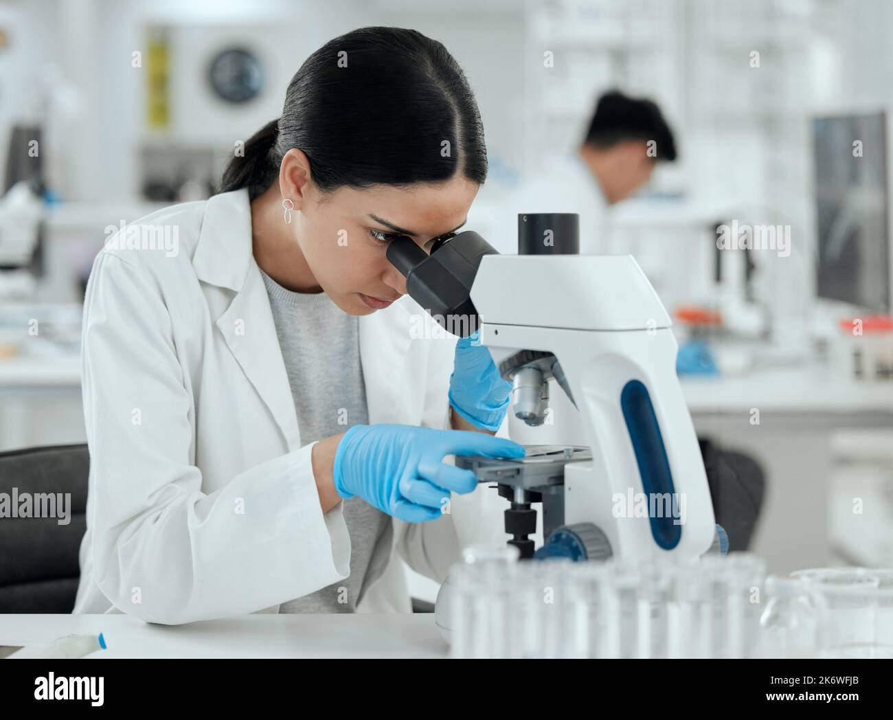 Ricerca di una cura. una giovane donna che usa un microscopio in un laboratorio scientifico. Foto Stock