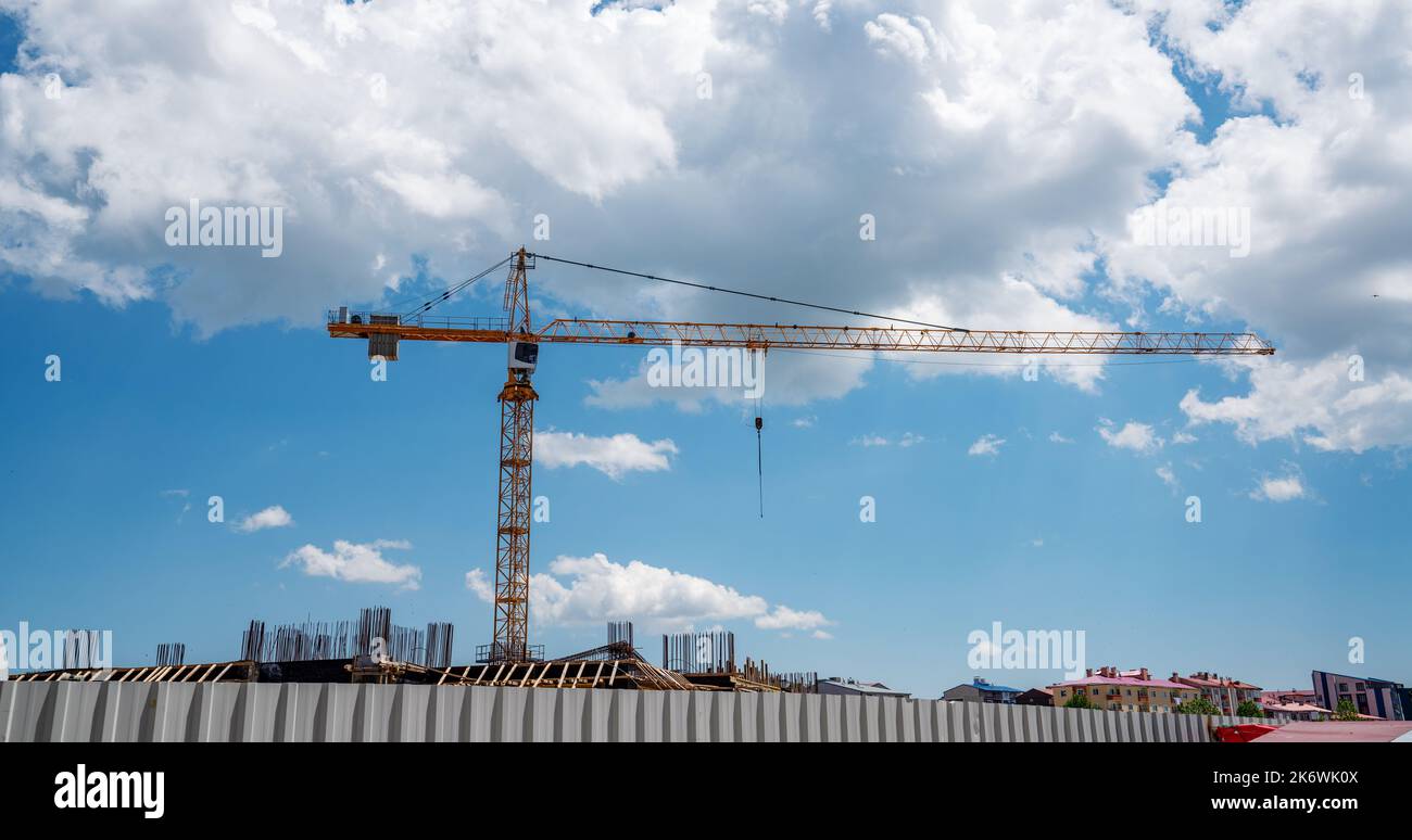 Costruzione di un edificio con una gru da costruzione contro il cielo blu con nuvole di fondo. Foto di alta qualità Foto Stock
