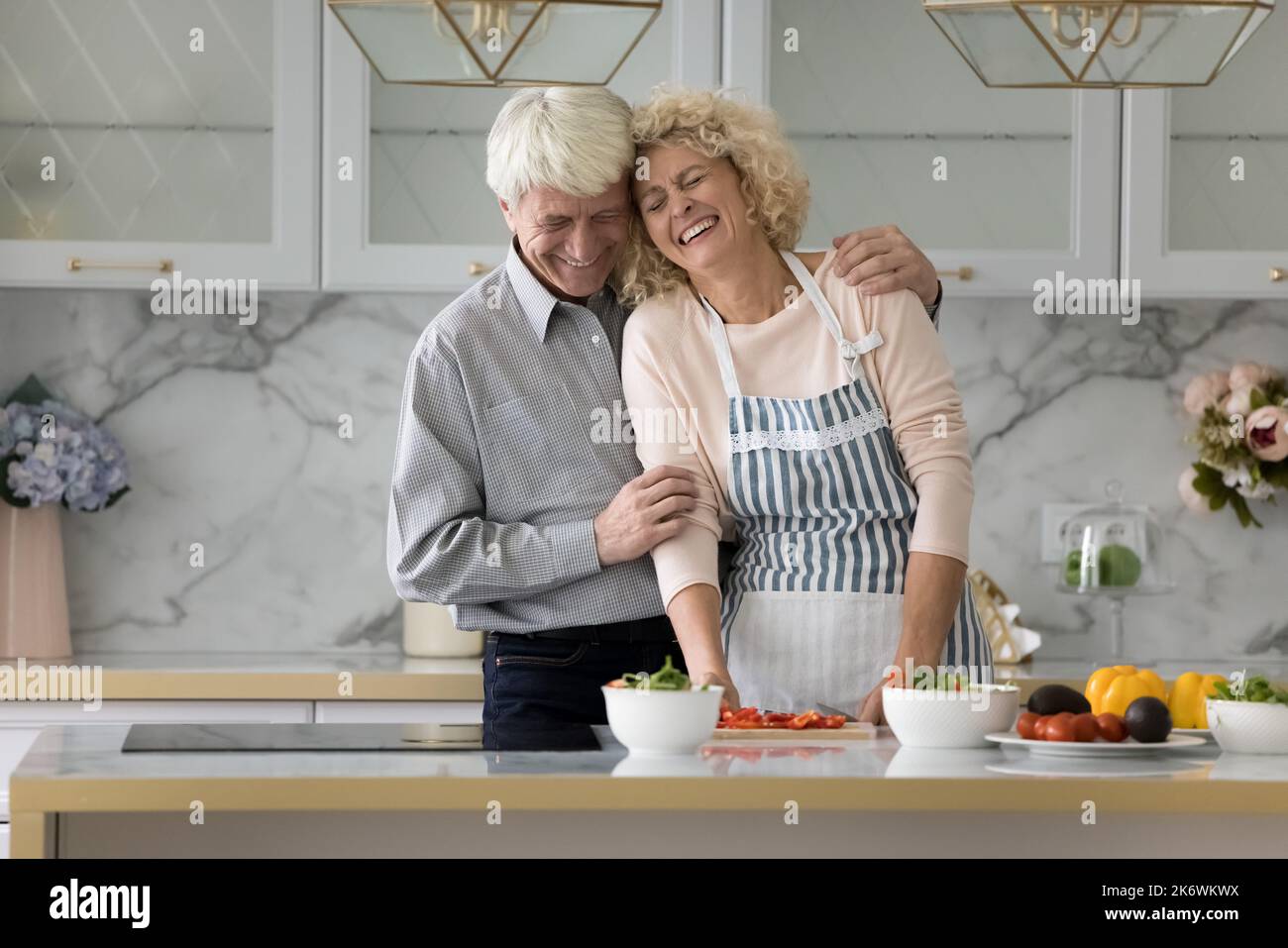 Felice coppia più anziana cucina e ridere in cucina moderna Foto Stock