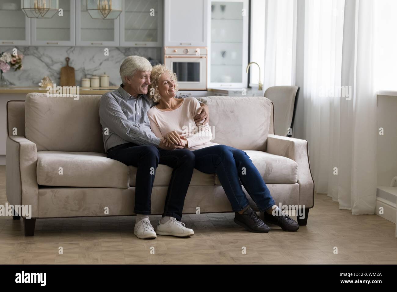 La coppia più anziana sogna di guardare in lontananza rilassarsi insieme sul divano Foto Stock