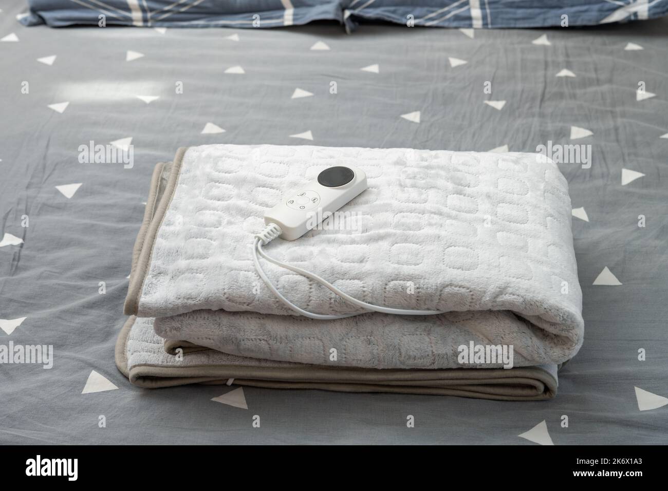 coperta elettrica ripiegata con controller sul letto a composizione orizzontale Foto Stock