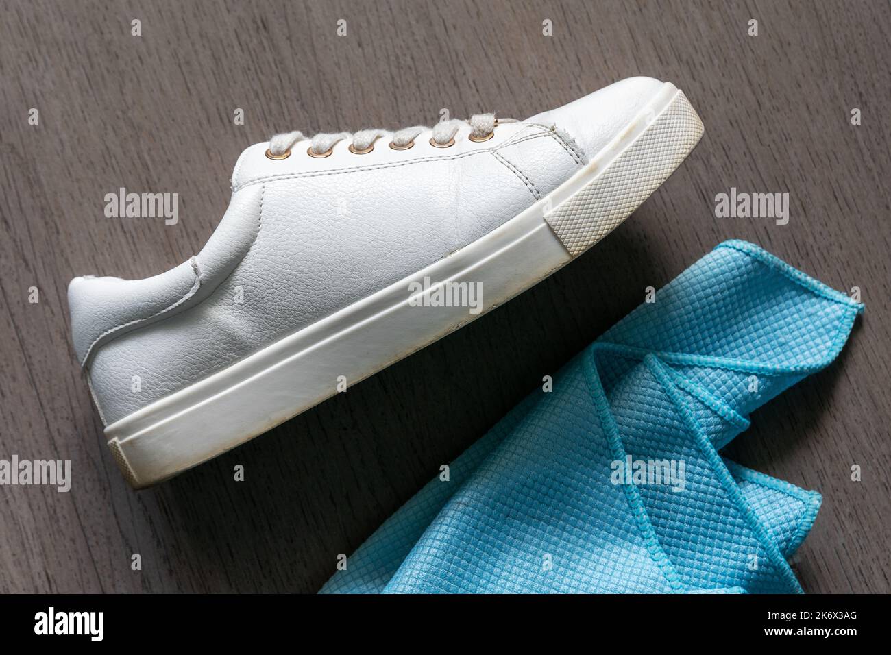 Una sneaker bianca accanto a un panno per la pulizia Foto Stock