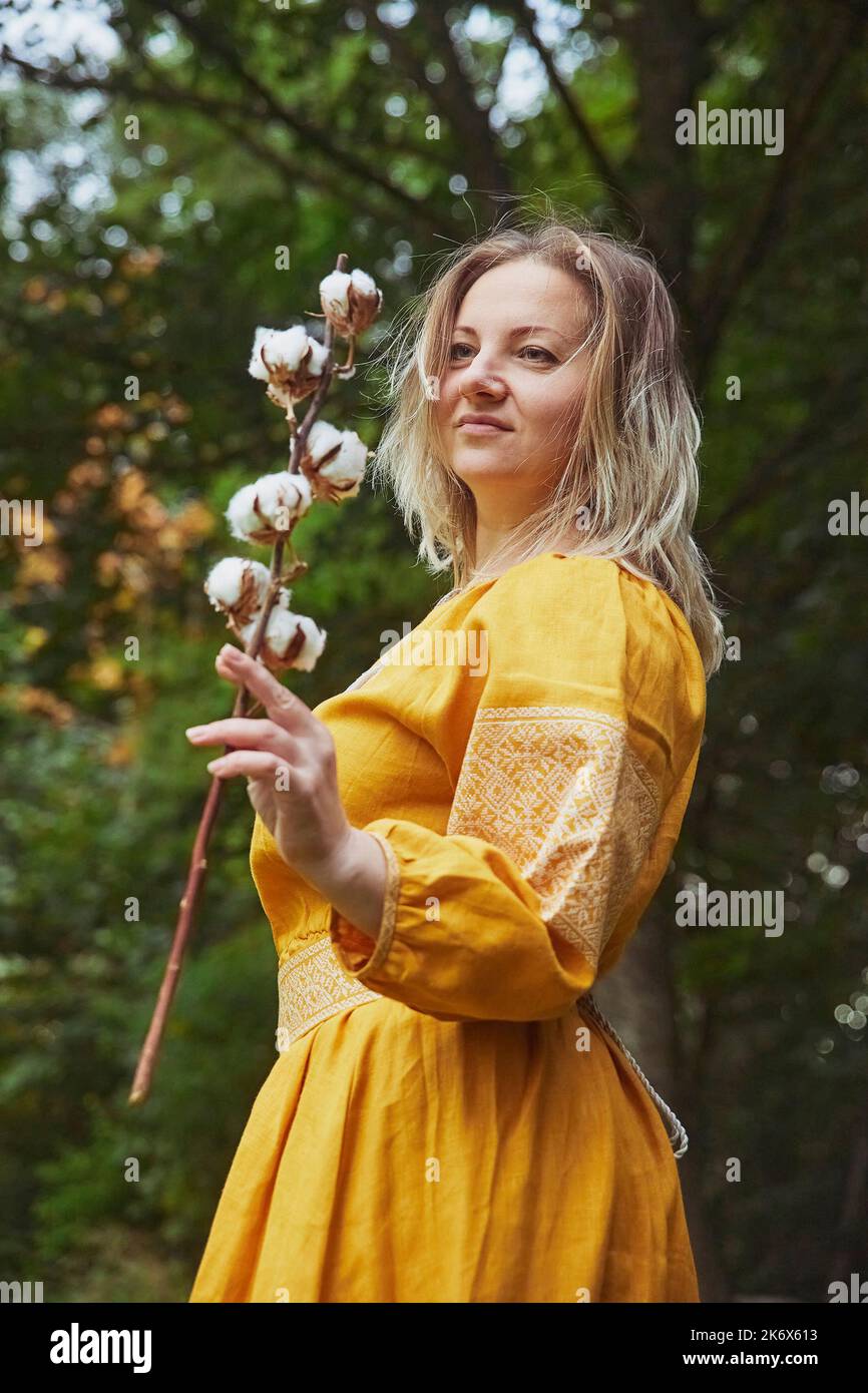 Bella donna Ucraina in vestito ricamato tiene un rametto di cotone Foto Stock