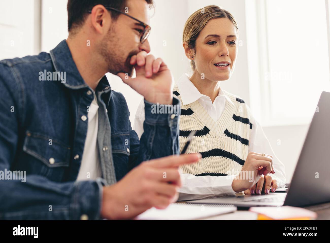 Due uomini d'affari che hanno una discussione con i loro clienti durante una riunione in linea. Uomini d'affari moderni che hanno una videoconferenza in un'offi creativa Foto Stock