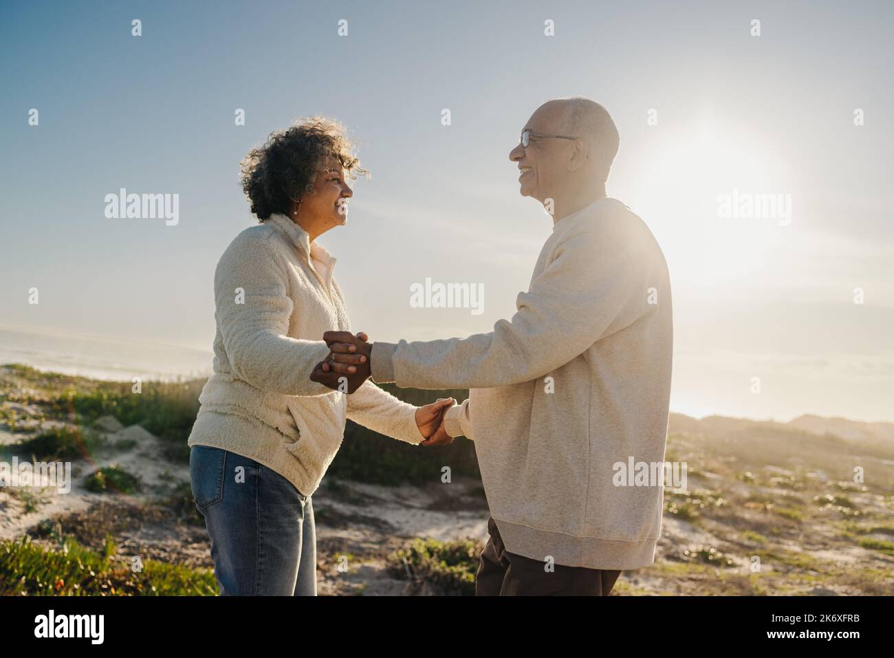 Coppia anziana sorridente mentre ballava insieme in spiaggia. Felice coppia anziana che si trova vicino all'oceano. Coppia romantica godendo la loro r Foto Stock