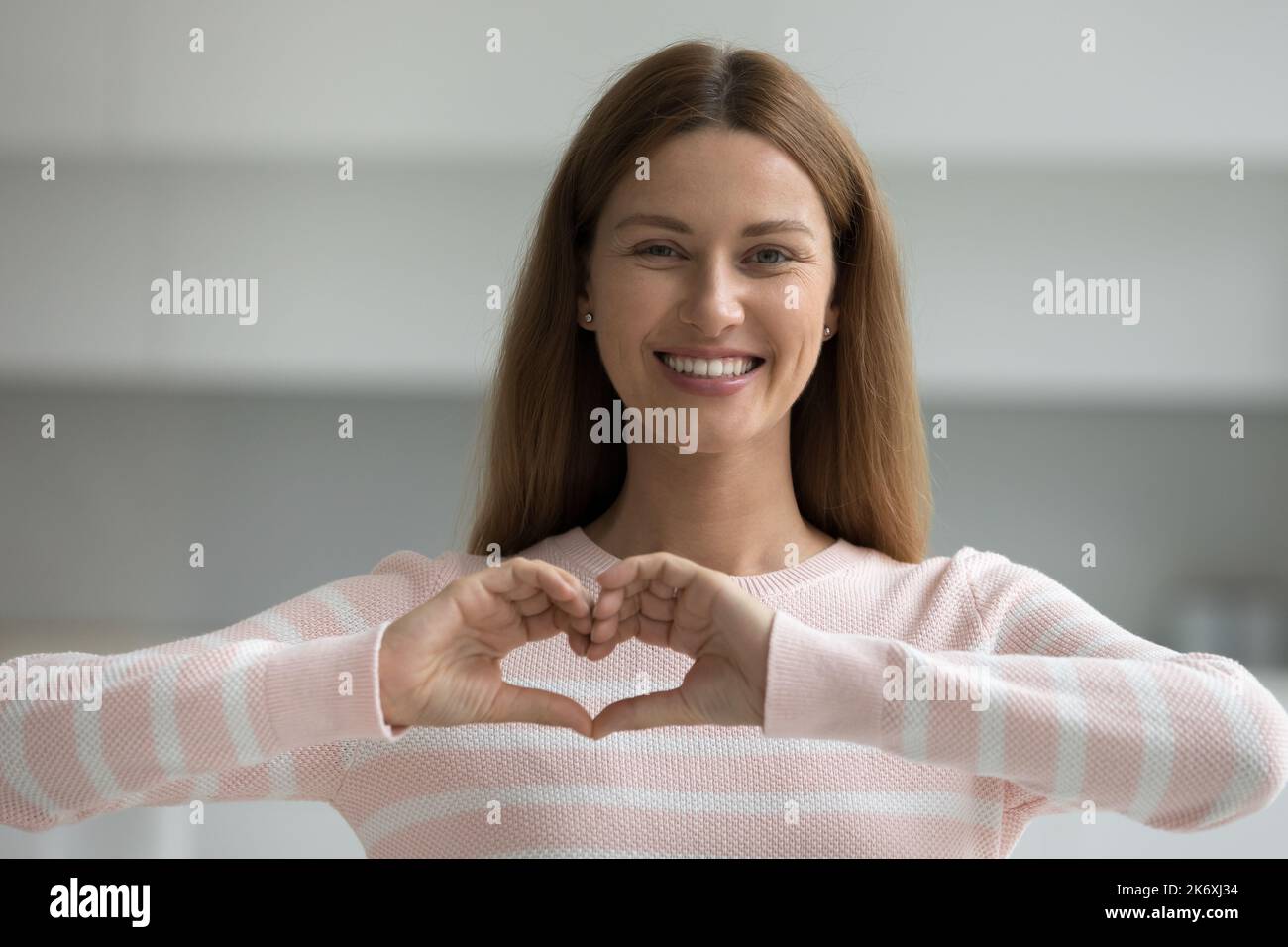 Bella donna che mostra il segno del cuore con le dita Foto Stock